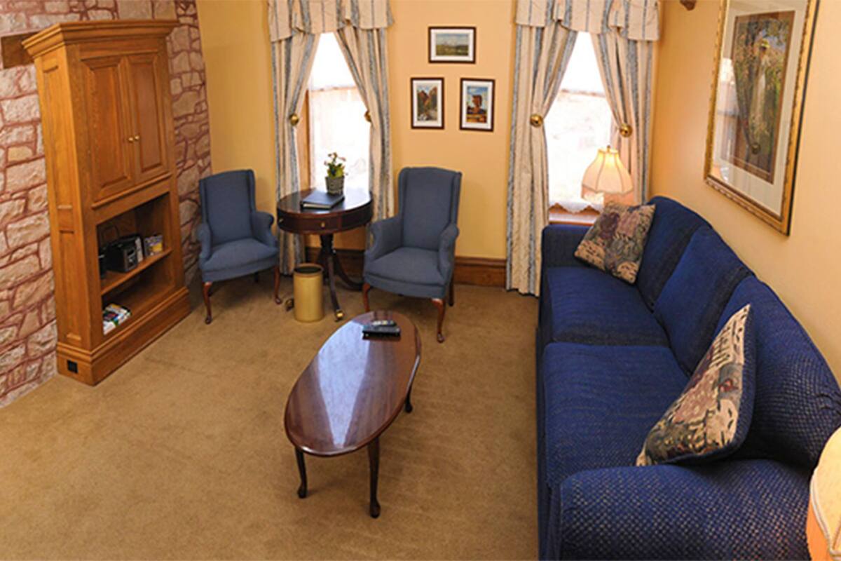 A living room with a blue sofa, two armchairs, a wooden cabinet, and a coffee table.