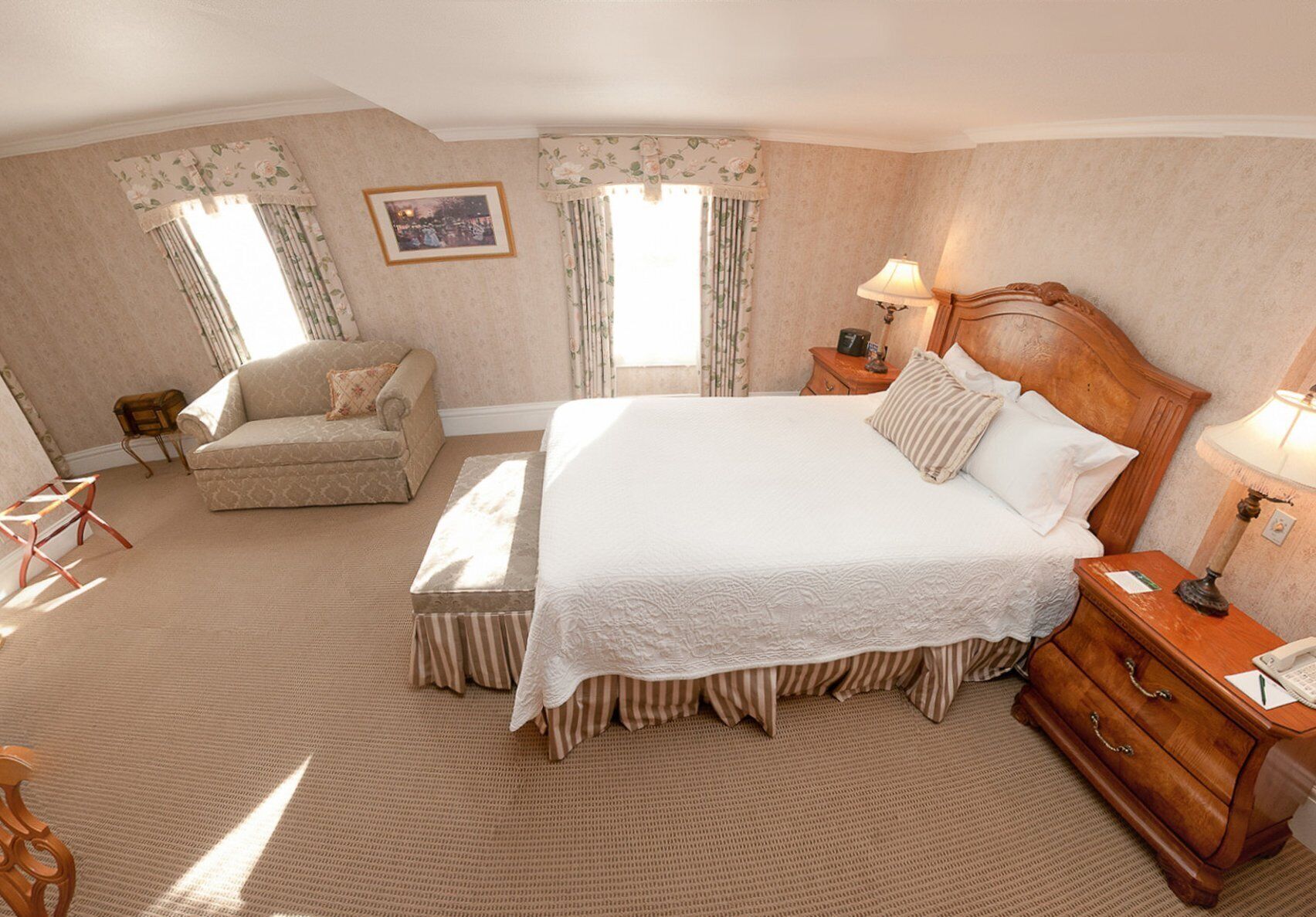 A spacious bedroom with a large bed, a sofa, and a wooden nightstand.