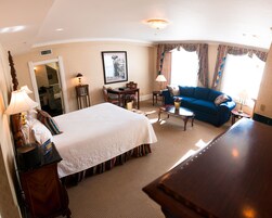 A hotel room with a large bed, a blue sofa, a small table, and a desk with a chair.