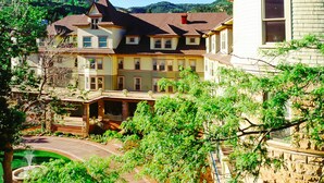 A large, multi-story house with a prominent turret and a wrap-around porch. - Cliff House at Pikes Peak (Manitou Springs)