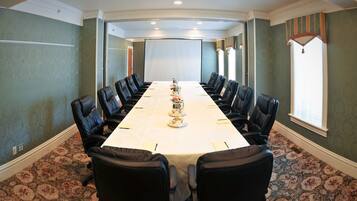 A conference room with a long table, black leather chairs, and patterned carpet.