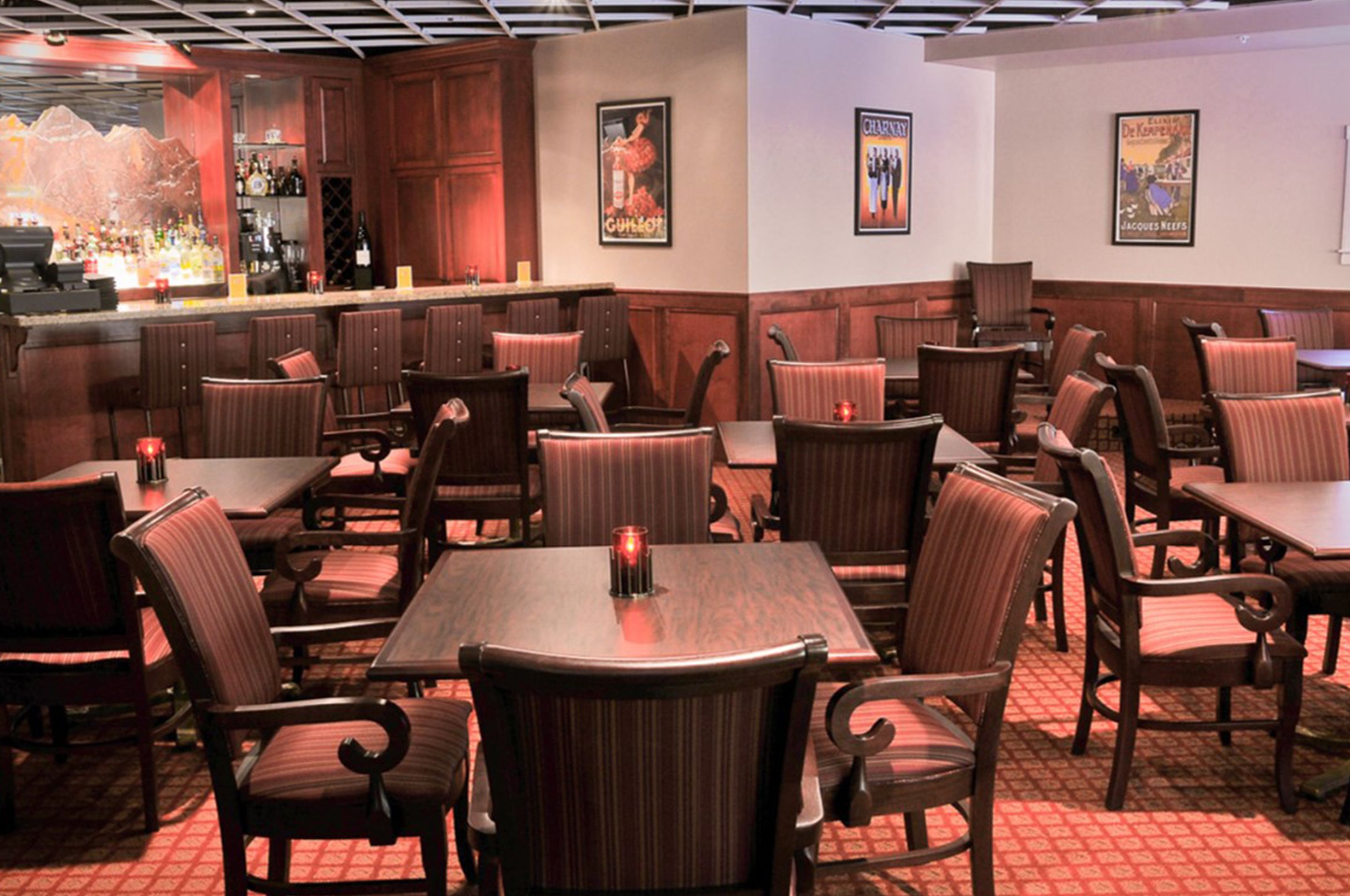 A restaurant with wooden tables and chairs, a bar area, and wall decorations.
