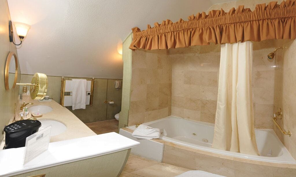 A bathroom with a bathtub, a shower, a sink, and a vanity.