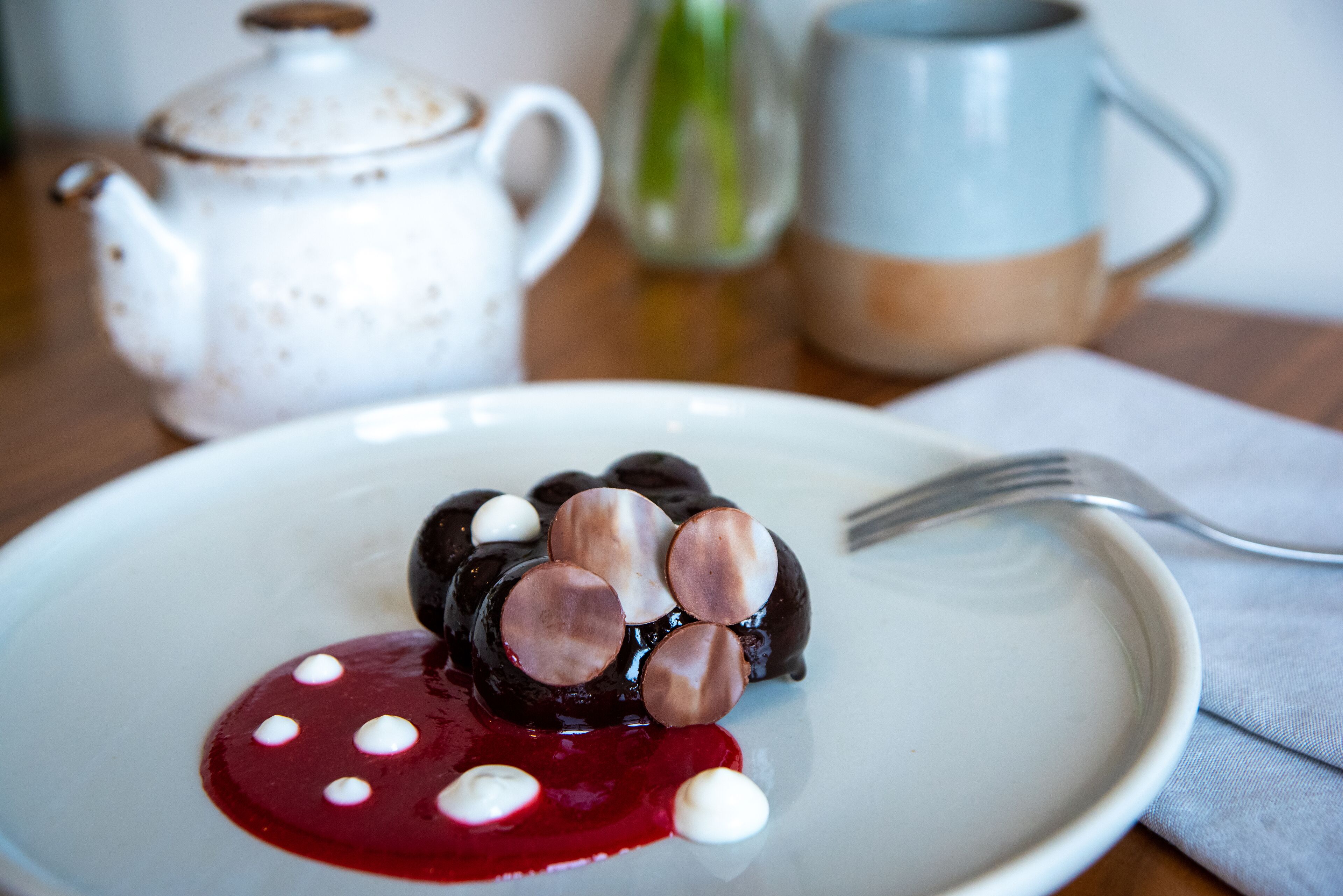A plate with a dessert, a teapot, and a mug on a table.