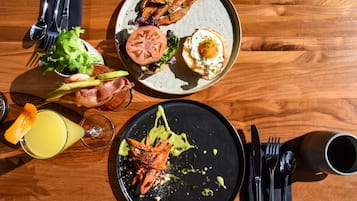 A wooden table with a plate of food, a glass of drink, and cutlery.