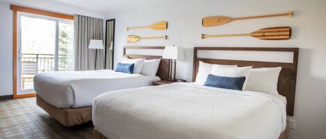 A hotel room with two beds, a balcony, and wooden paddles on the wall.