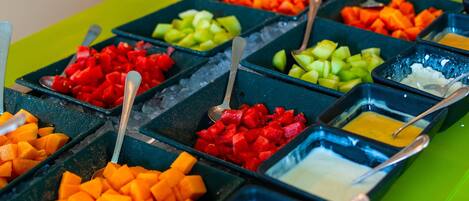 A buffet with various fruits and dips.