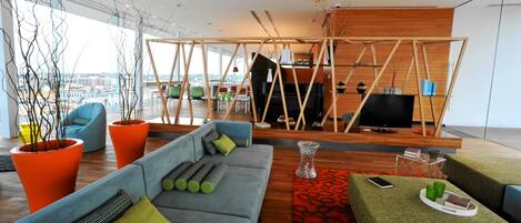 A modern living room with a blue sofa, orange planters, and a red patterned rug.