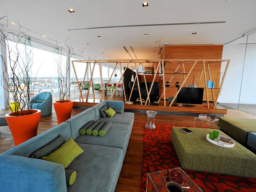 A modern living room with a blue sofa, orange planters, and a red patterned rug.