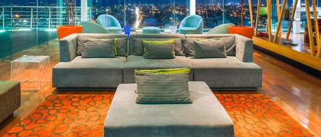 A modern lounge area with a grey sofa set, striped cushions, and a clear glass coffee table.