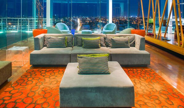 A modern lounge area with a grey sofa set, striped cushions, and a clear glass coffee table.