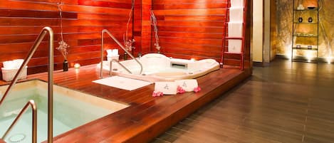 A spa area with a wooden wall, a bathtub, and a small sink.