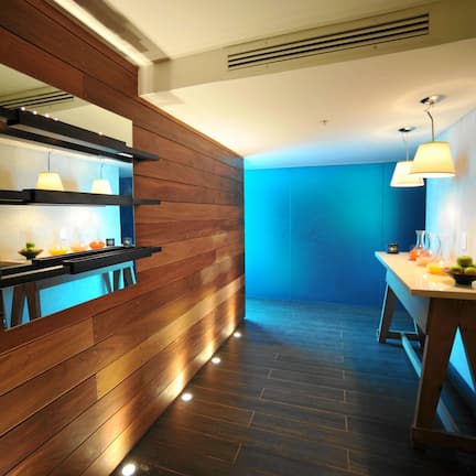 A modern kitchen with wooden paneling, a built-in stove, and a dining area with a table and chairs.