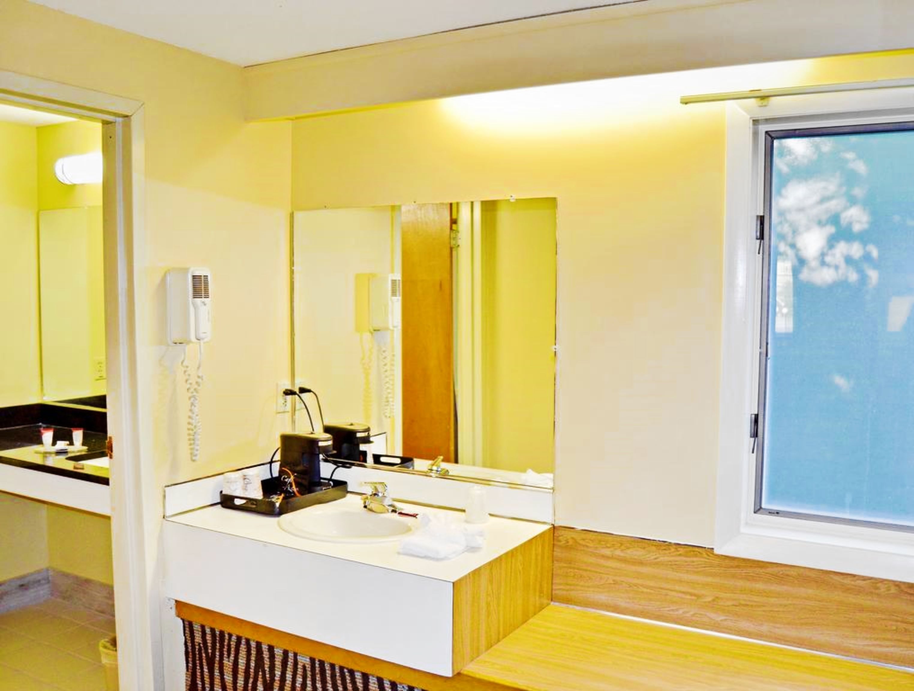 A bathroom with a white sink, a mirror, a hairdryer, and a telephone.