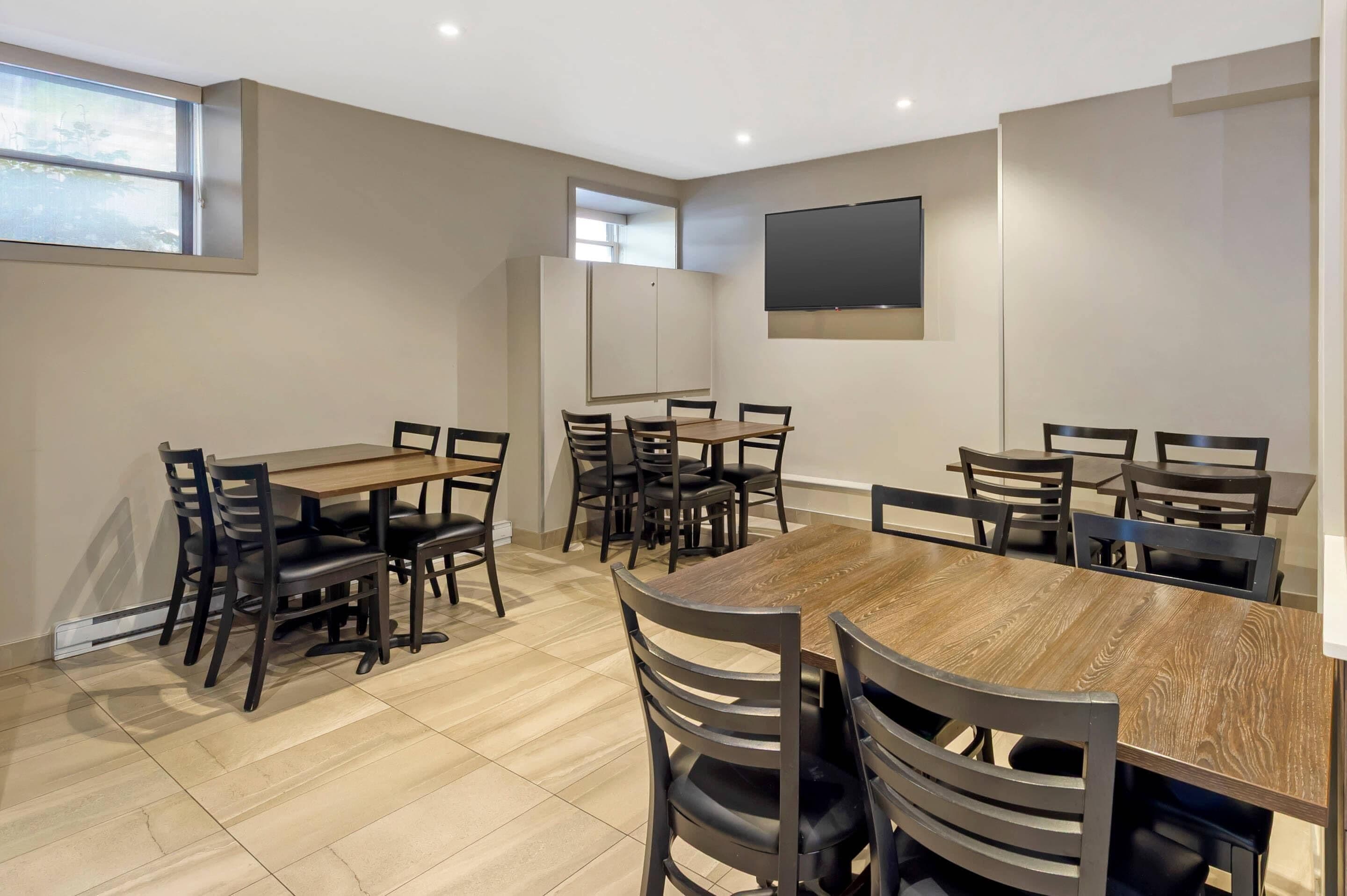 Une salle de conférence avec une grande table en bois, de nombreuses chaises, un tableau blanc et un téléviseur à écran plat fixé au mur.