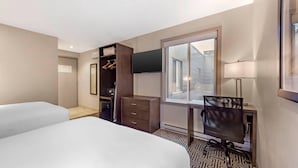 A hotel room with two beds, a desk, a chair, a wardrobe, a TV, and a window with a view. - Quality Inn Centre-Ville (Montreal)