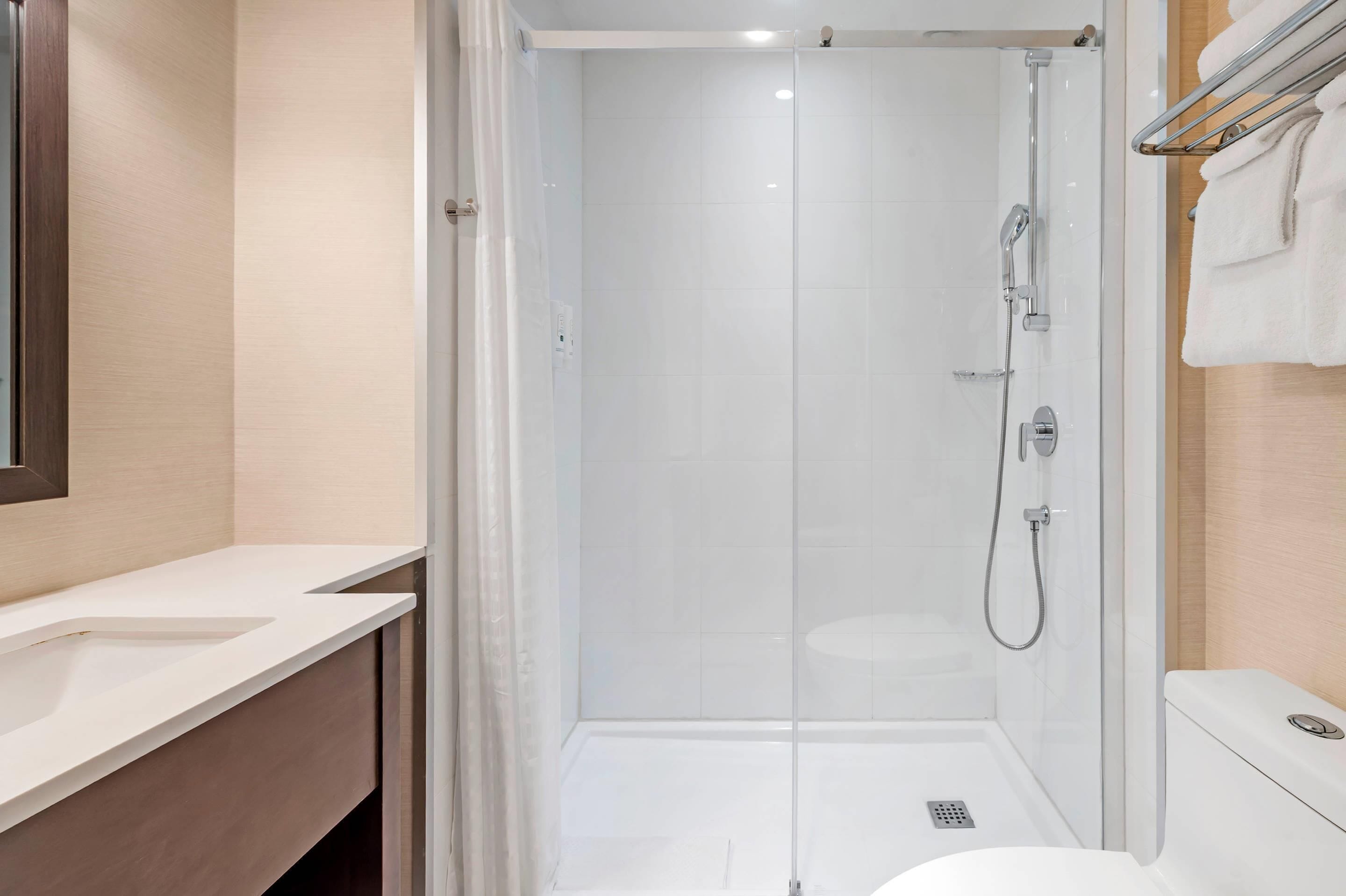A modern bathroom with a glass-enclosed shower, a white sink, and a toilet.