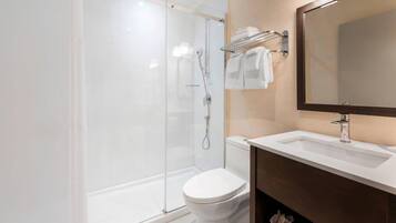 Une salle de bain moderne avec une douche à parois de verre, des toilettes blanches et un meuble-lavabo avec un miroir.