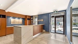 A reception area with a marble counter, wooden cabinets, and a cityscape painting. - Quality Inn Centre-Ville (Montreal)
