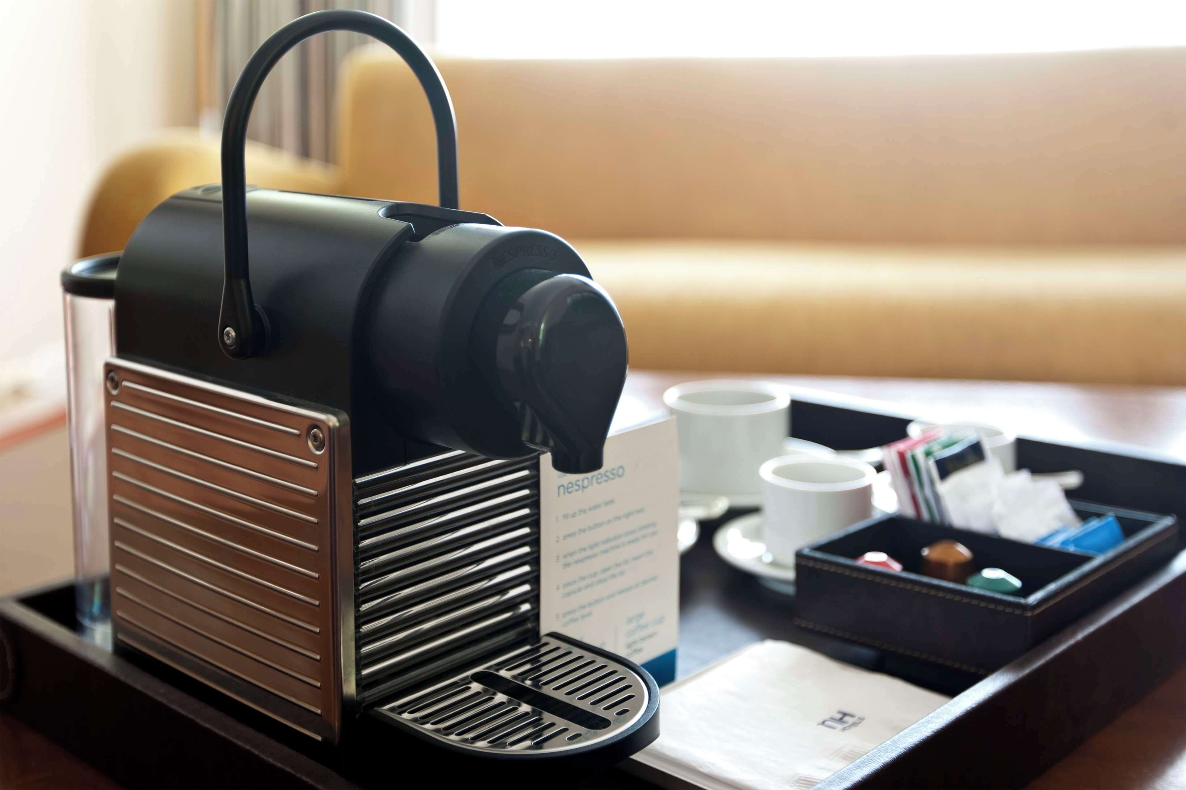 A coffee machine on a tray with a menu and a cup of coffee.