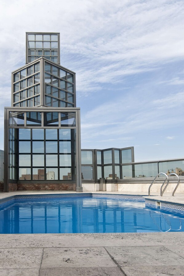 Una piscina al aire libre de temporada, tumbonas