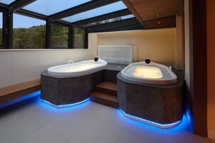 Un baño moderno con dos jacuzzis separados, un calentador integrado y vistas al exterior a través de amplios ventanales.