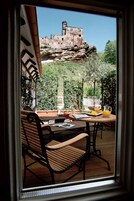 Un patio con una mesa, sillas, una jarra de jugo de naranja y un plato de comida.