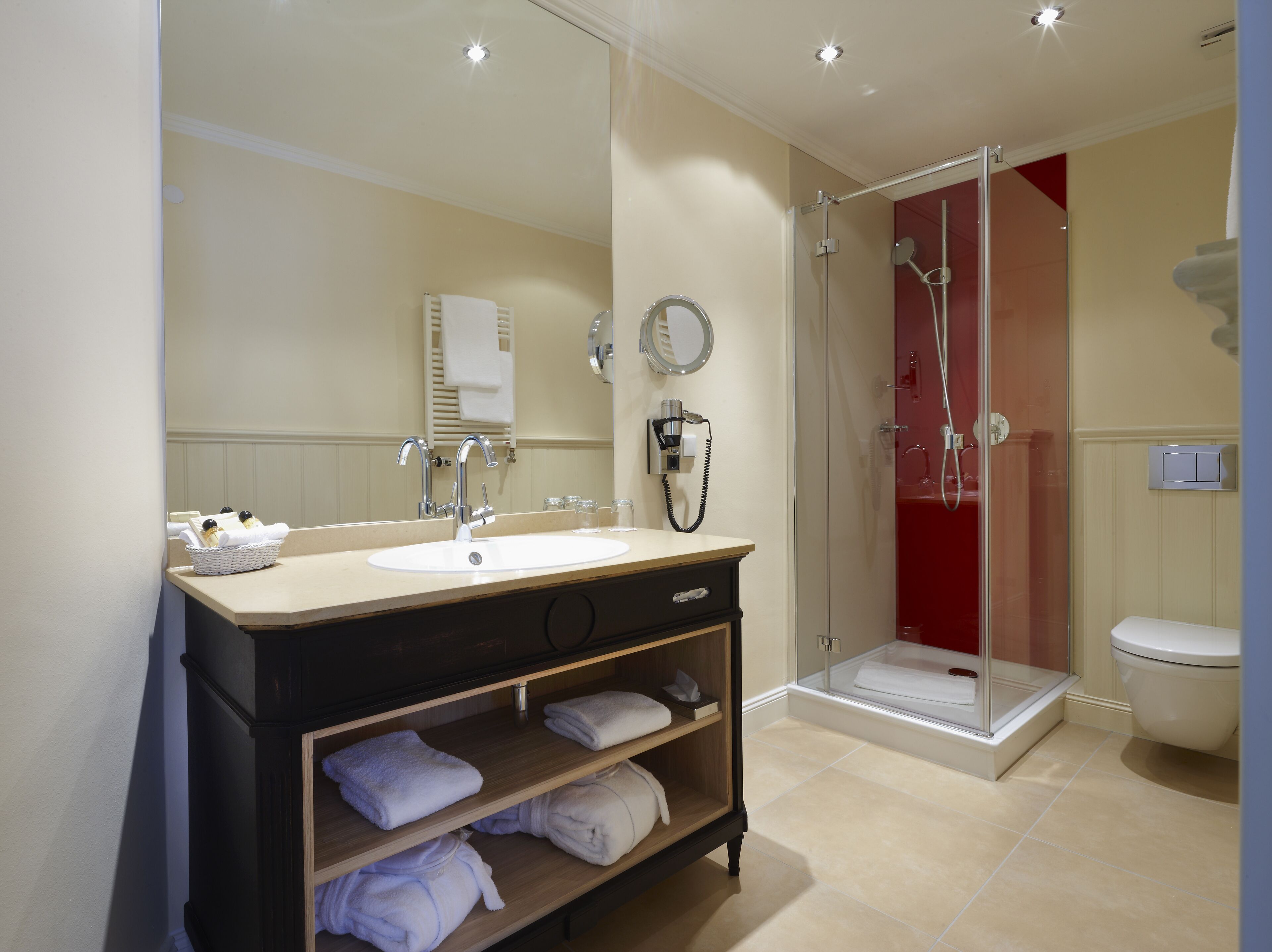 A modern bathroom with a sink, mirror, towel rack, shower, and toilet.