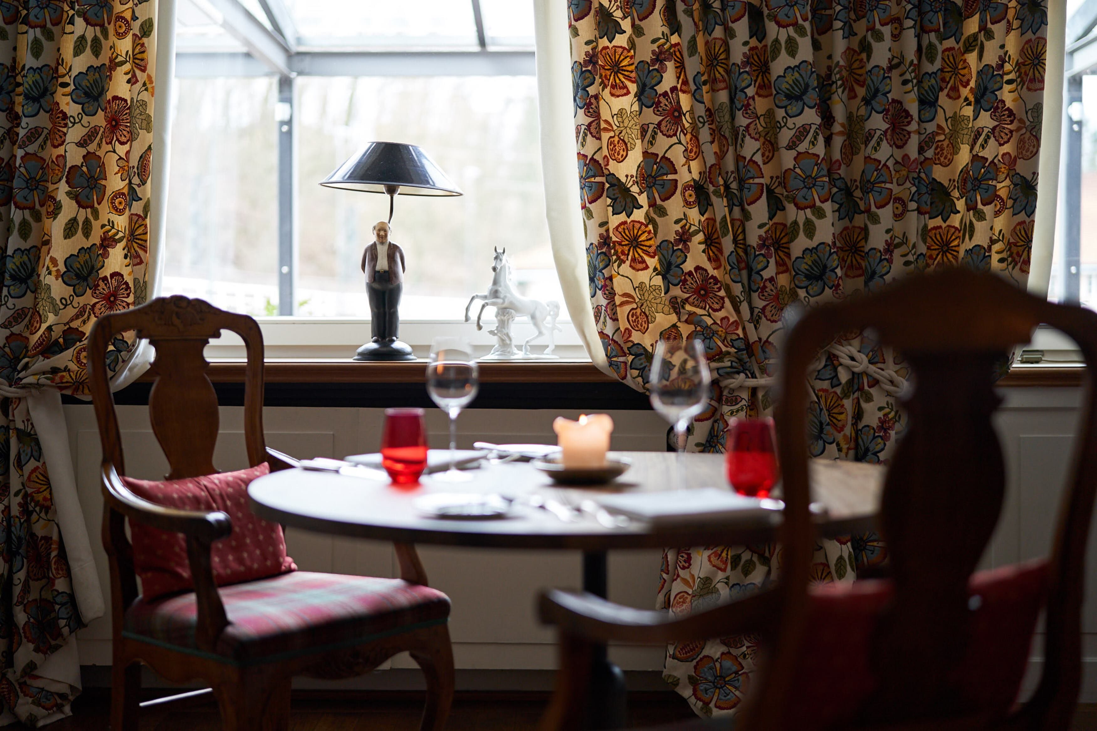 A dining area with a table set for two, a candle, and a lamp.