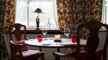 A dining area with a table set for two, a candle, and a lamp.