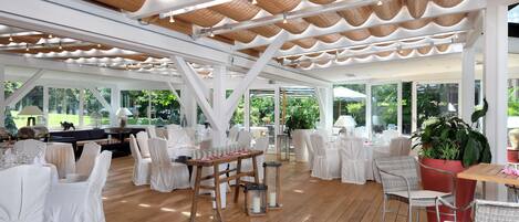 Un comedor interior con sillas y mesas blancas y suelo de madera.