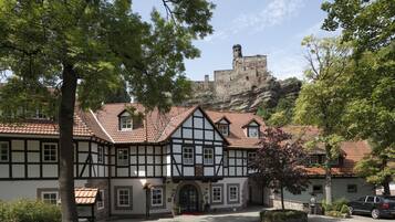 Un edificio tradicional con entramado de madera y un castillo de piedra al fondo.