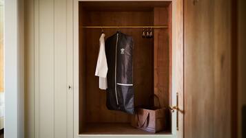 A walk-in closet with a hanging rack, a coat, and a handbag.