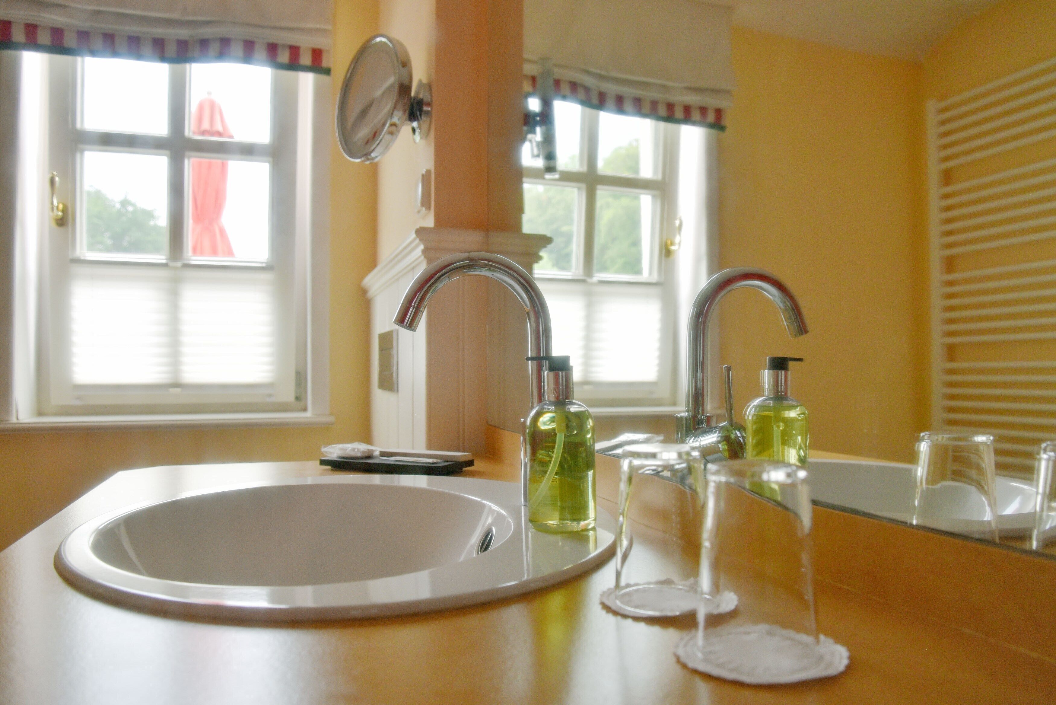 A bathroom with a white sink, two faucets, and two bottles of liquid soap.