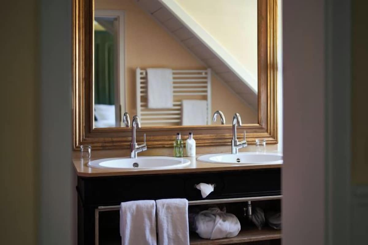 Une salle de bain avec deux lavabos, un grand miroir et un porte-serviettes.