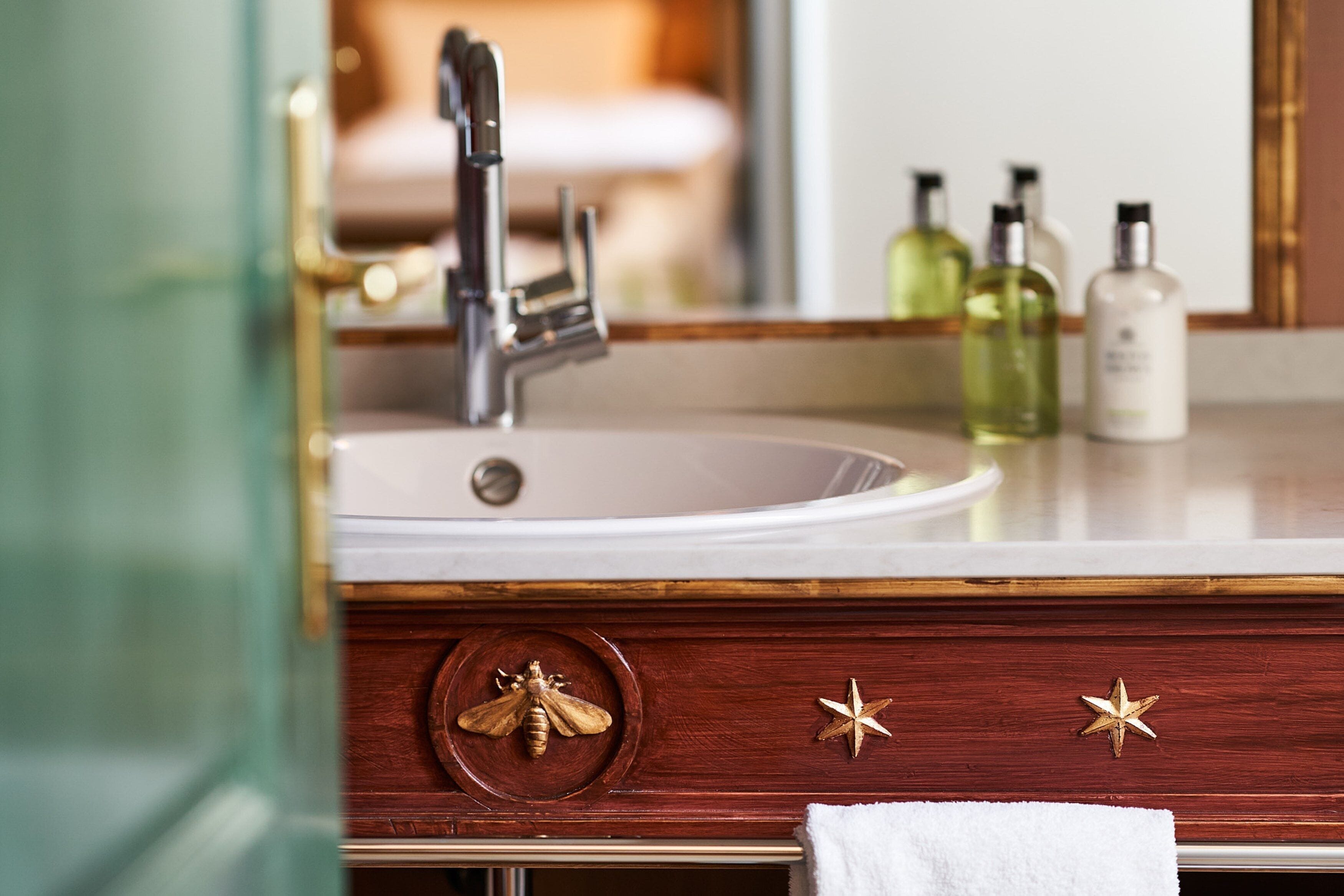 A bathroom vanity with a white sink, gold faucet, and decorative wooden drawer handles.