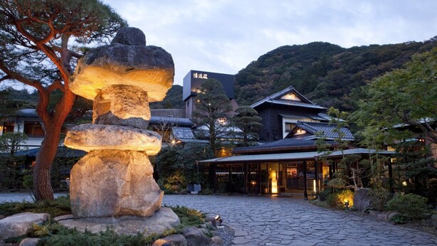 A traditional Japanese building with a stone pathway leading to it, surrounded by trees and a large rock sculpture. - Inn Seiryuso (Shimoda)
