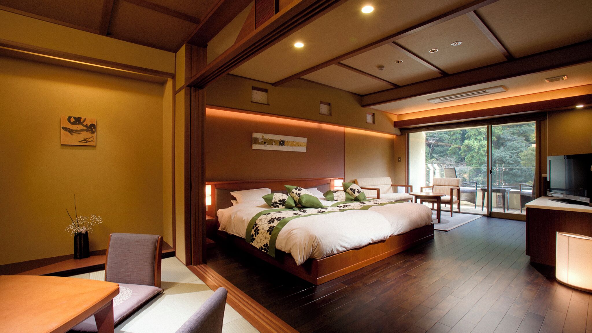 A hotel room with a large bed, a TV, a desk, and a balcony with a view.
