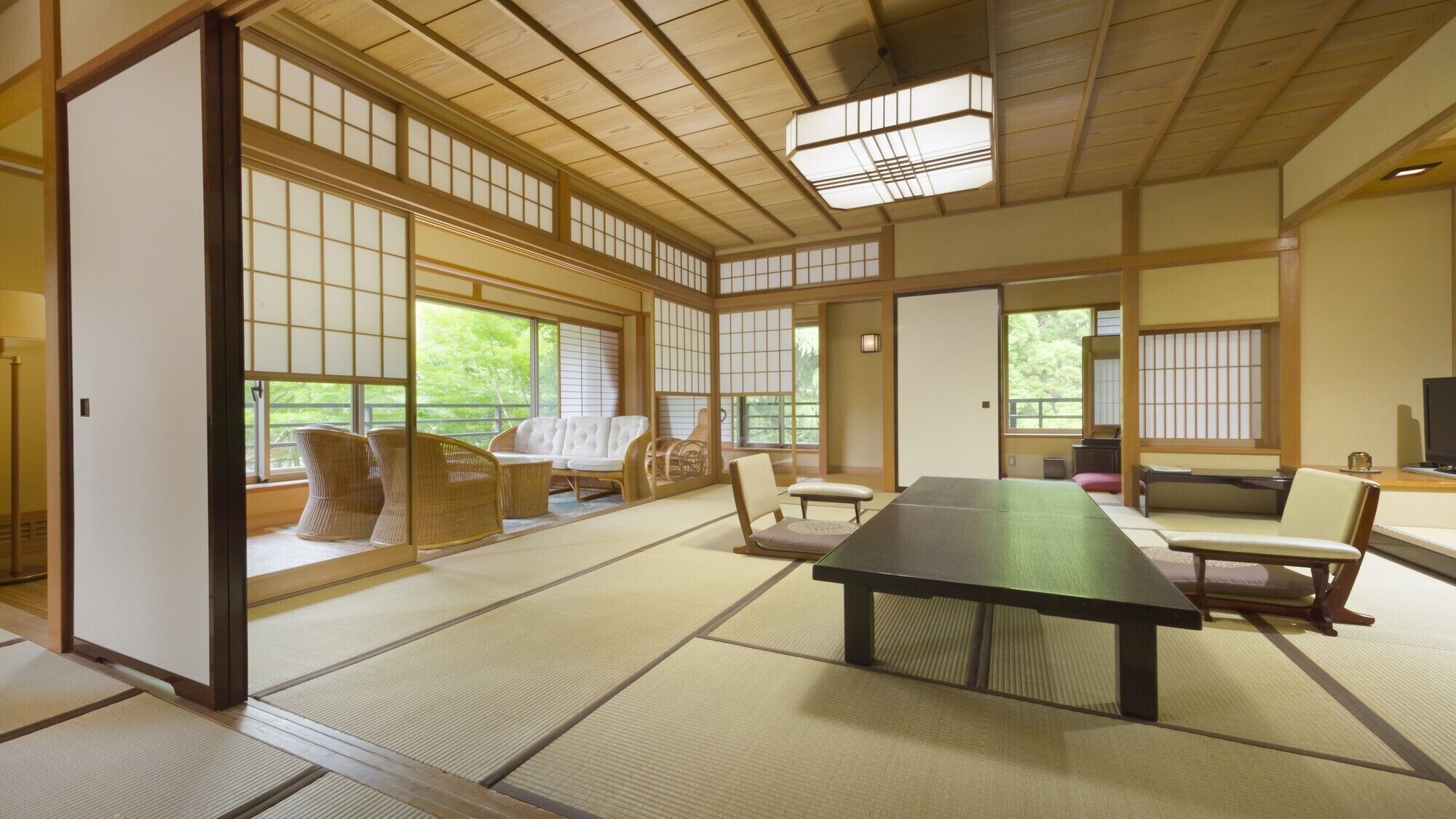 A tatami mat room with a tatami mat table, chairs, and a television.
