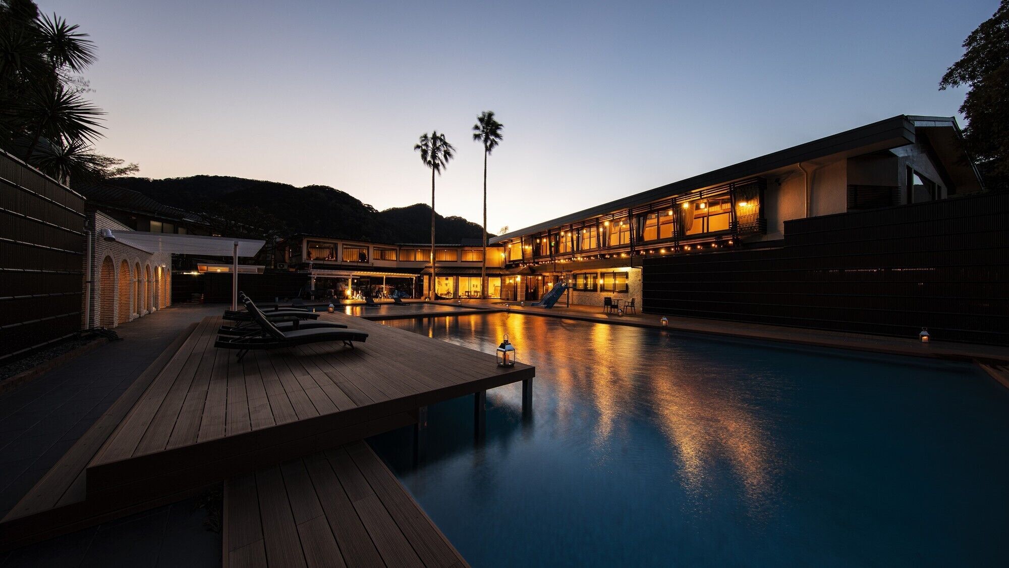 A modern resort with a swimming pool, lounge chairs, and a covered deck area.