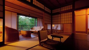 A traditional Japanese room with tatami flooring, a low table, and a cushioned chair. - Inn Seiryuso (Shimoda)