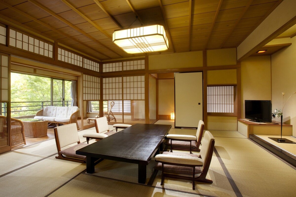 A traditional Japanese-style room with tatami flooring, a low table, and seating.