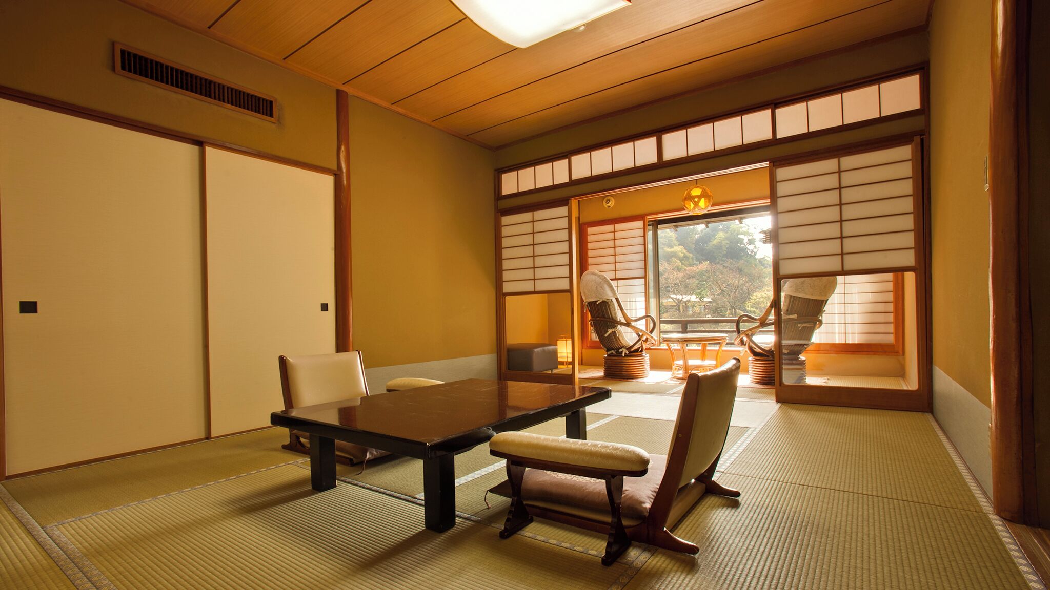 A traditional Japanese room with tatami flooring, a low table, and chairs.