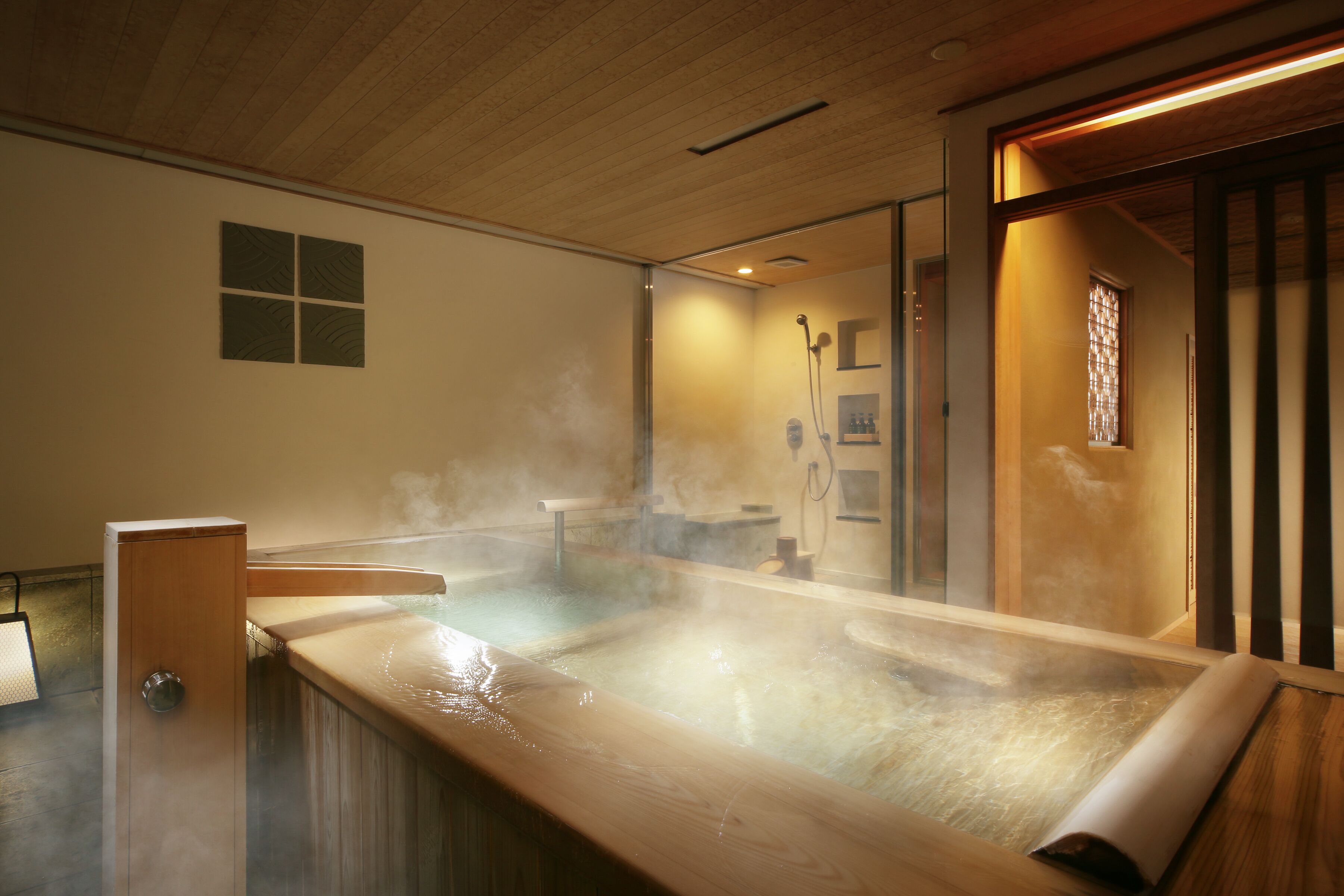 A hot spring bath with steam, wooden panels, and a small window.