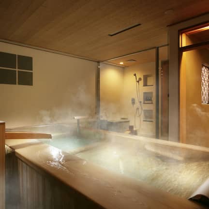A hot spring bath with steam, wooden panels, and a small window.
