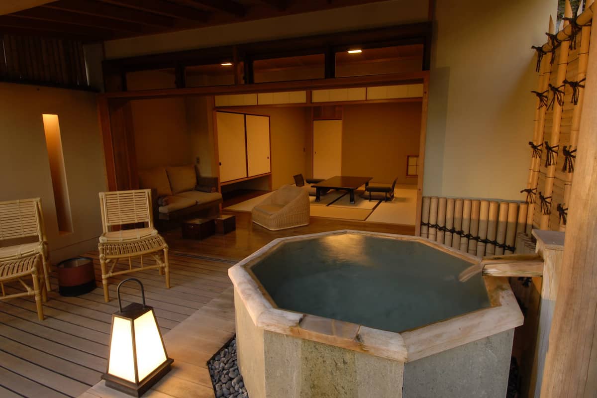 Un onsen japonés tradicional con un manantial de piedra caliente, muebles de madera y un farol.