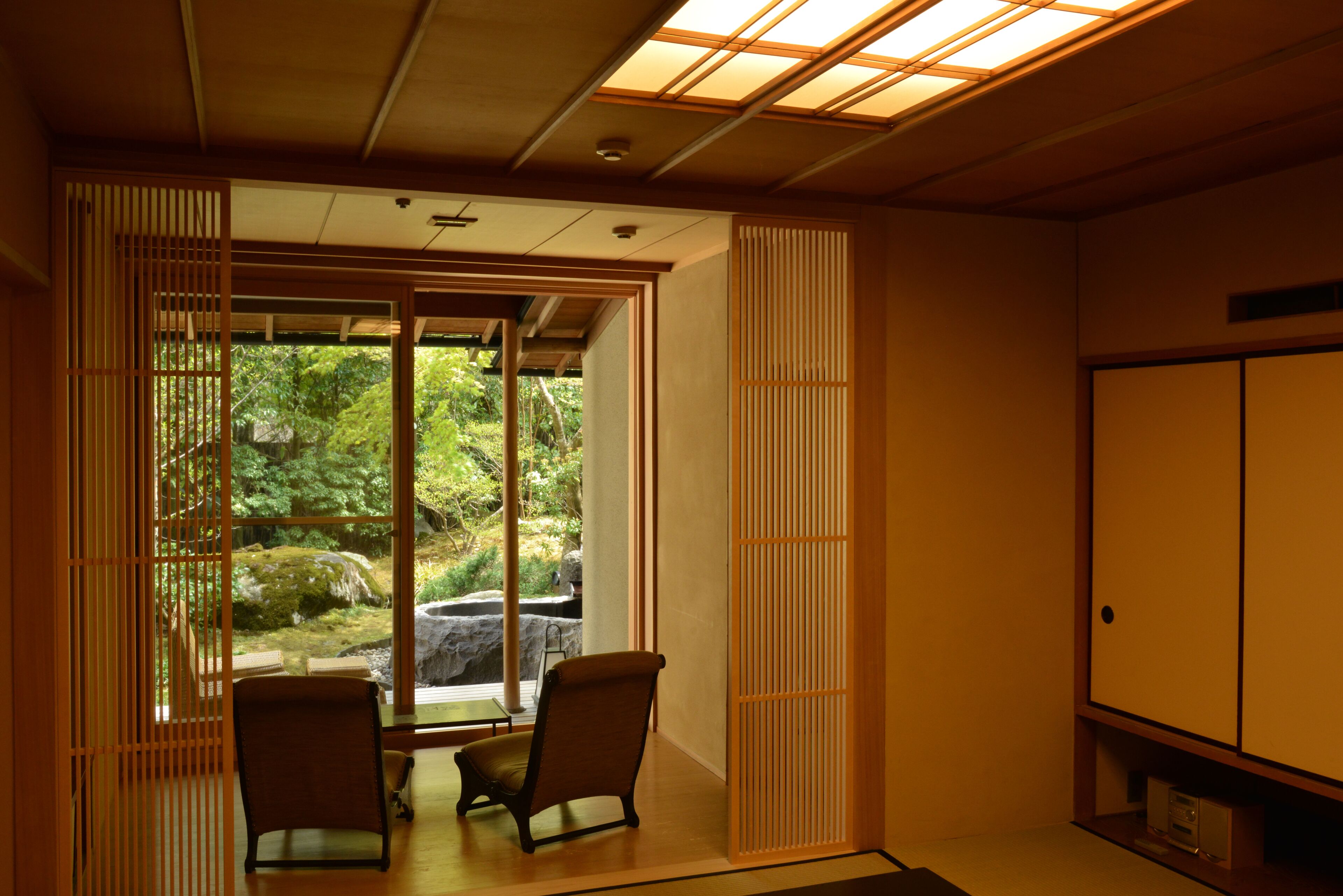 A traditional Japanese room with sliding doors, a tatami mat floor, and a view of a garden.