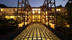 Un edificio moderno con fachada de vidrio y una estructura metálica geométrica en primer plano.
