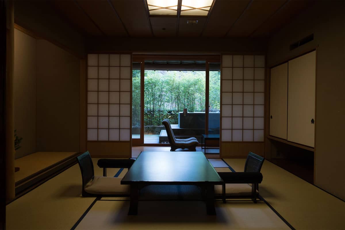 Una habitación tradicional japonesa con suelo de tatami, una mesa baja y puertas correderas.