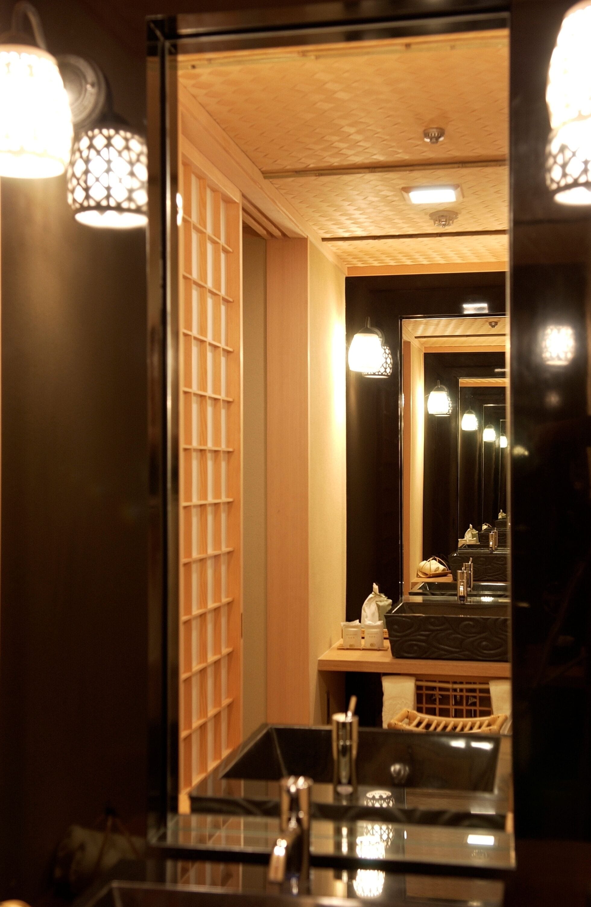 A bathroom with a glass sink, a mirror, and a towel rack.